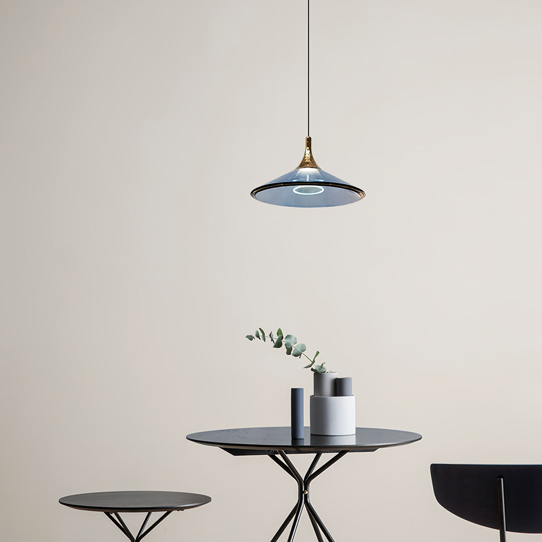Rise and fall pendant lights with blue frosted shade suspended over modern black table with decor