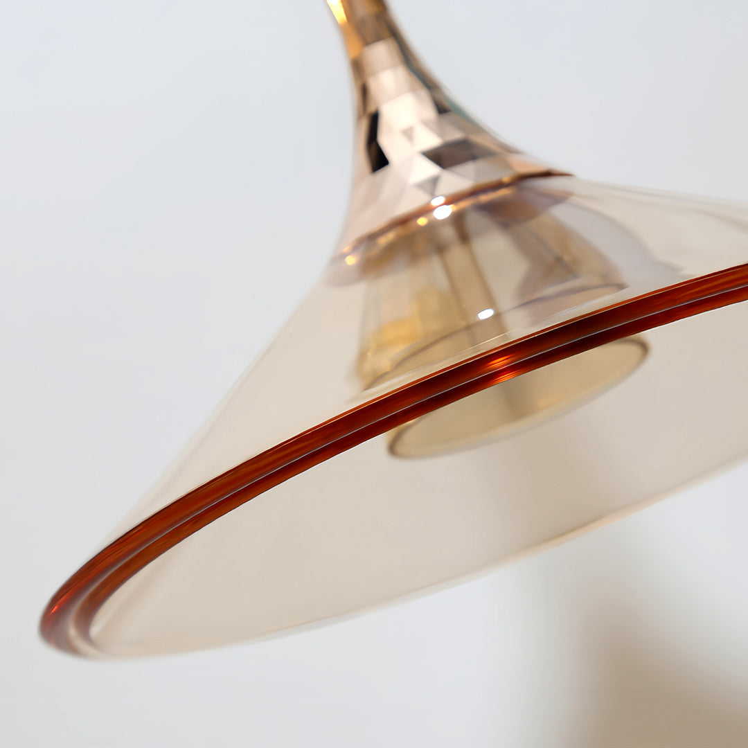 Detail view of rise and fall pendant lights highlighting red braided cord and metallic shade trim