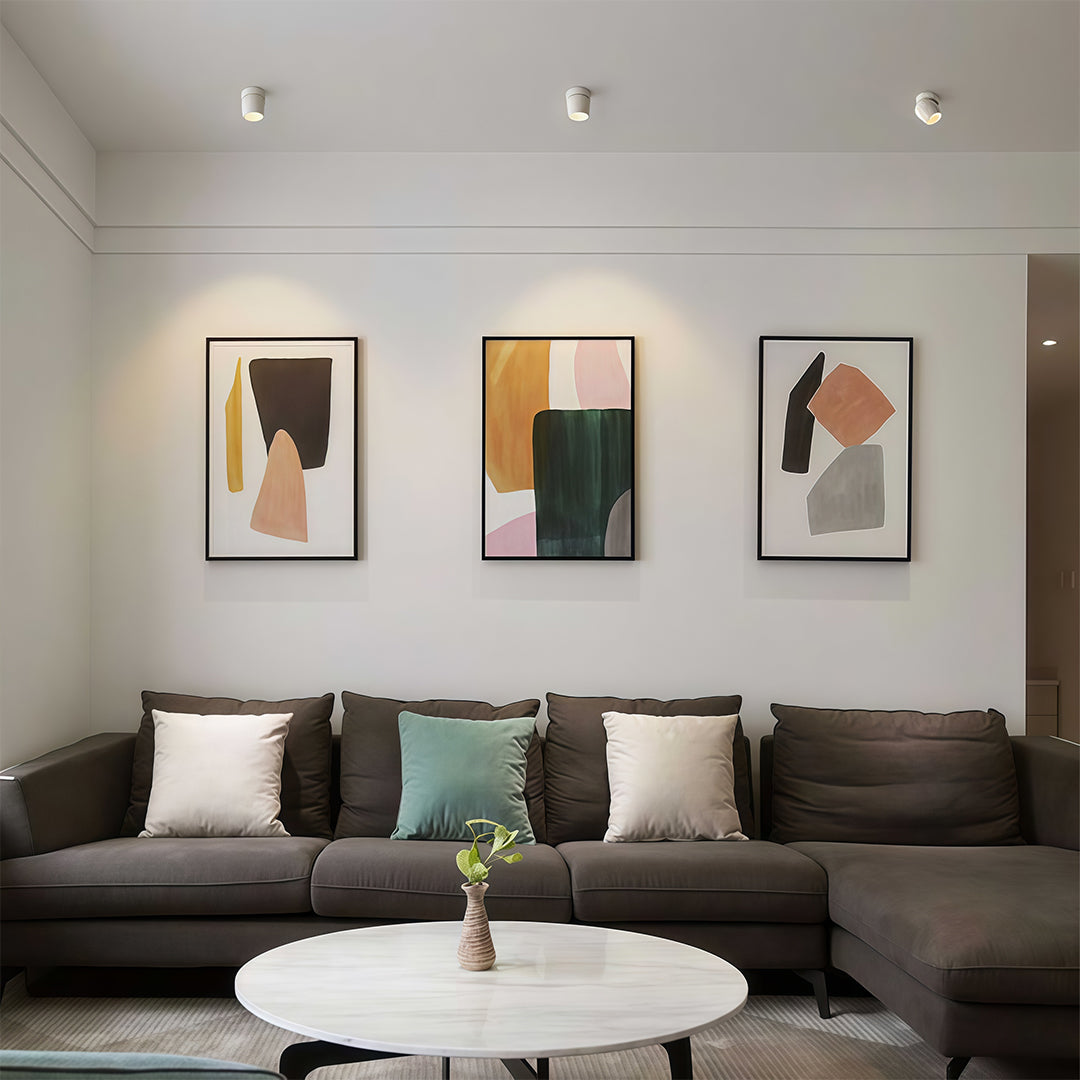 Rotating spotlights illuminating modern bedroom with grey walls, three framed art pieces, and neutral bedding