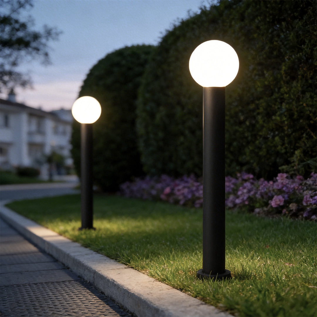 Round bollard lights with a black finish, providing warm light along a driveway.