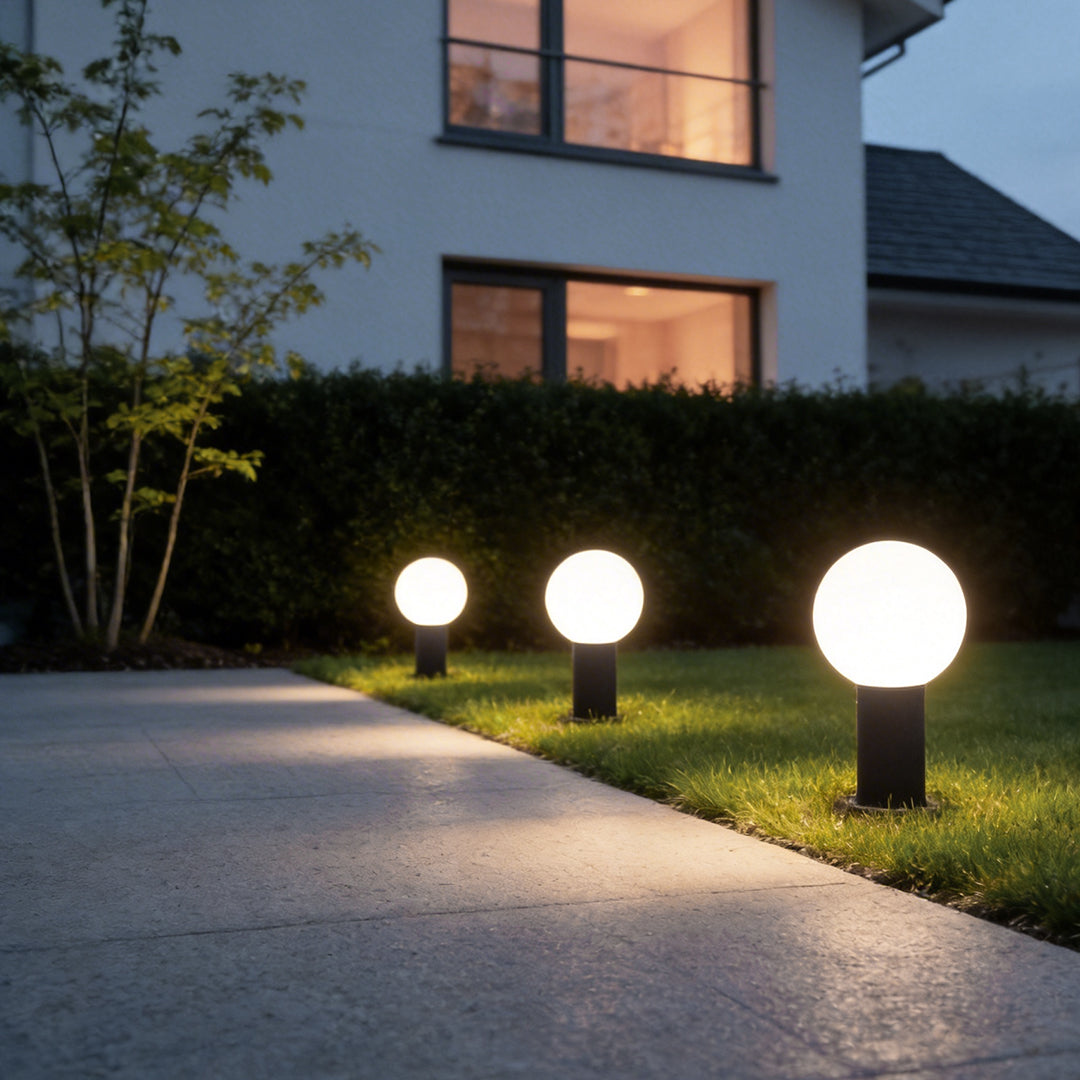 Round bollard lights with a spherical top, illuminating a garden pathway at dusk.