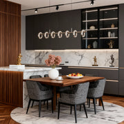 Stylish dining room illuminated by a round chandelier modern fixture with glowing glass rings.