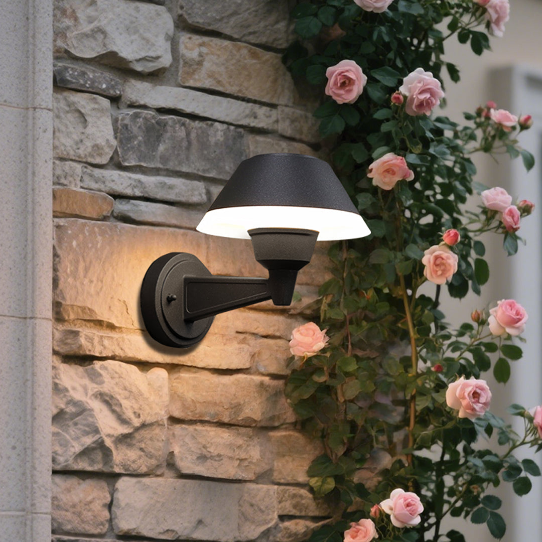 Modern black dome wall light with extending arm illuminating brick exterior wall at dusk