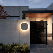 Round exterior wall lights with a modern design, mounted beside a contemporary house entrance.