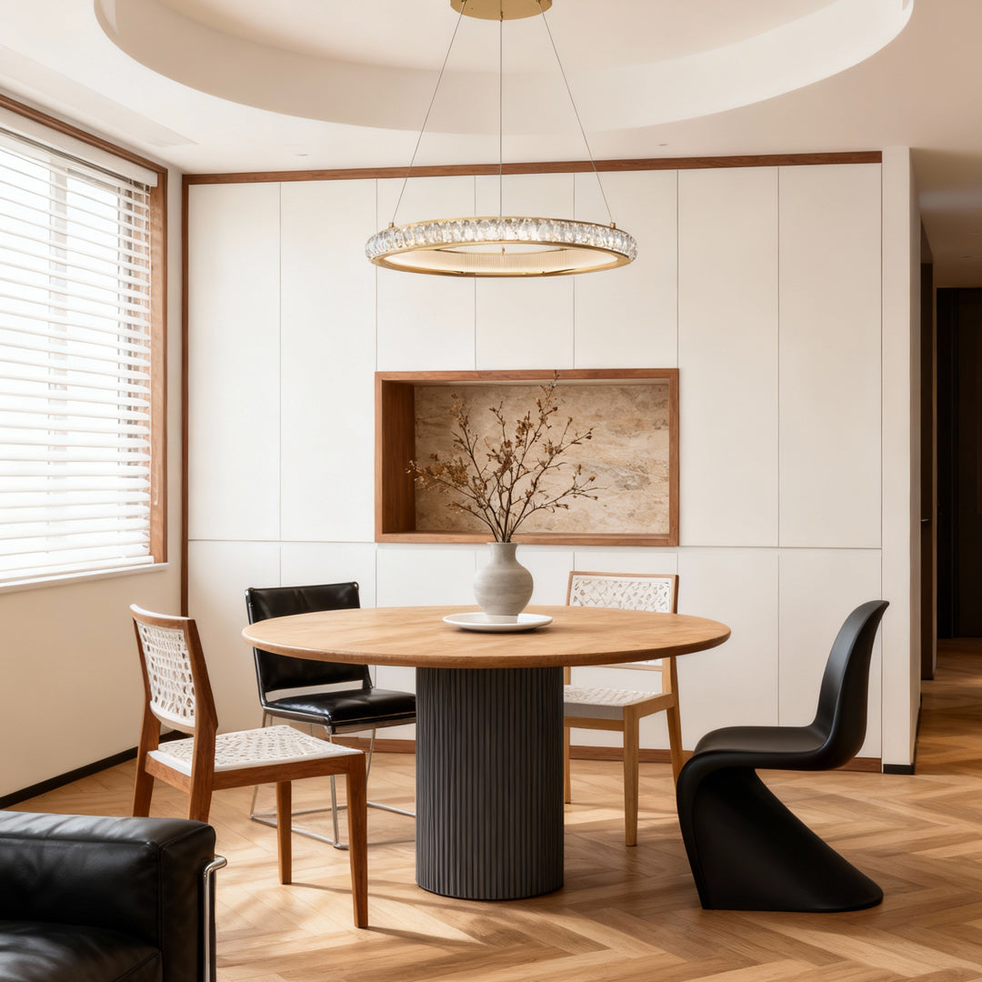 Round gold crystal chandelier suspended above dining table in bright contemporary space with artwork and modern furnishings