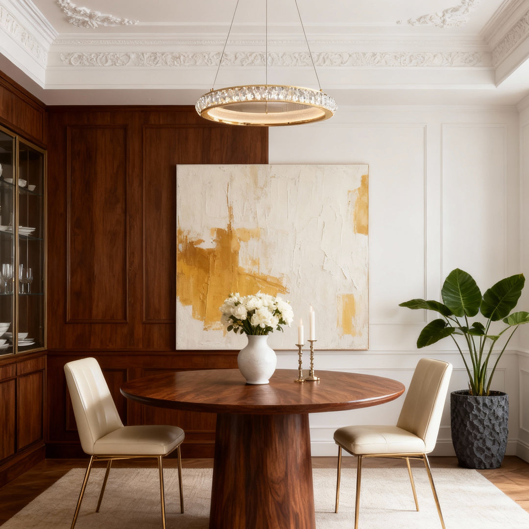 Round gold crystal chandelier creating focal point above round dining table with wood paneling and abstract art