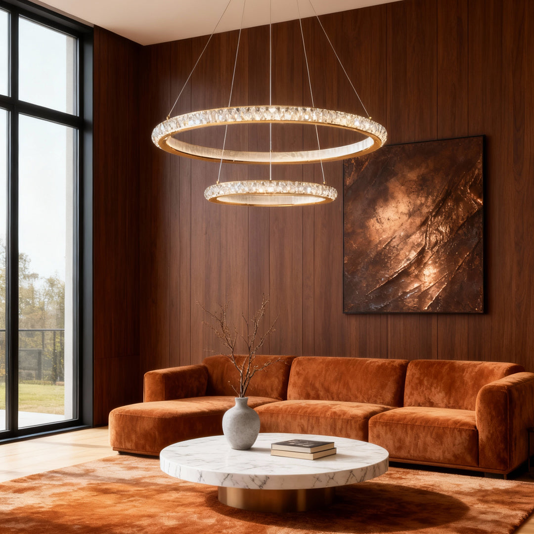 Round gold crystal chandelier with tiered rings illuminating luxury living room with cognac leather sofa and wood walls