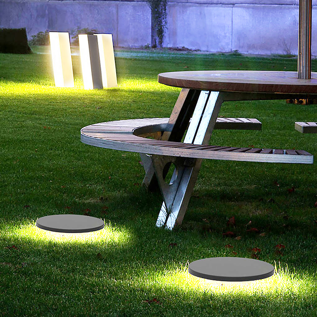 Round lawn lights installed on grass in a backyard landscape setting