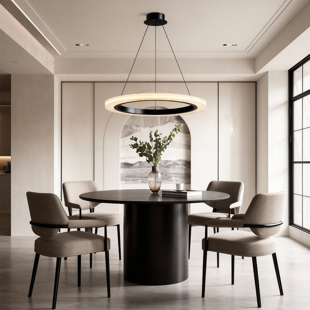 Round modern chandelier enhancing minimalist dining space with sculptural black table
