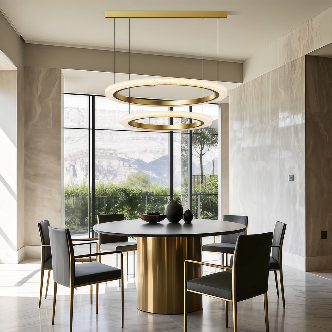 Modern luxury chandeliers above modern dining space with brass table and black chairs
