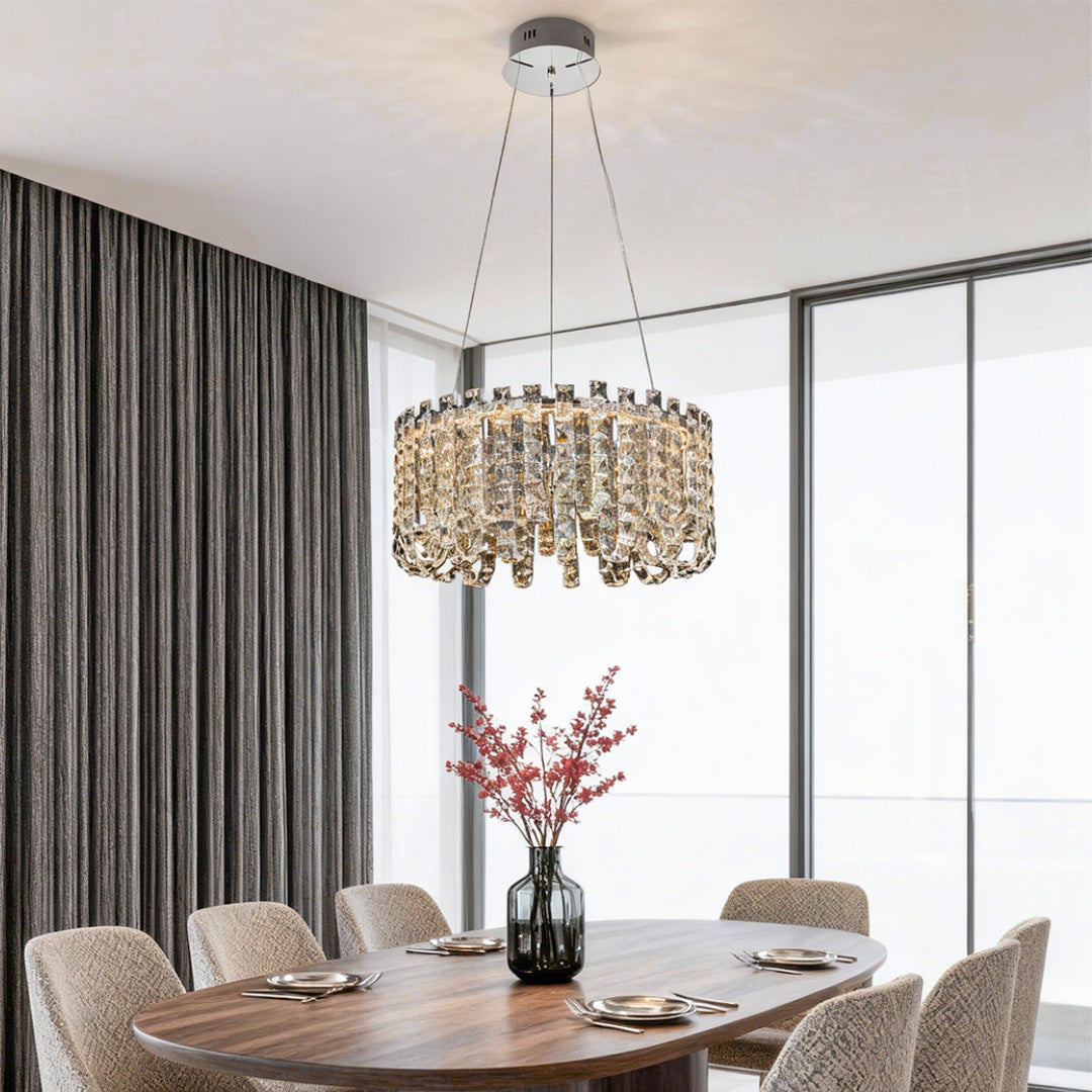 Dining room with round modern crystal chandelier above marble dining table.