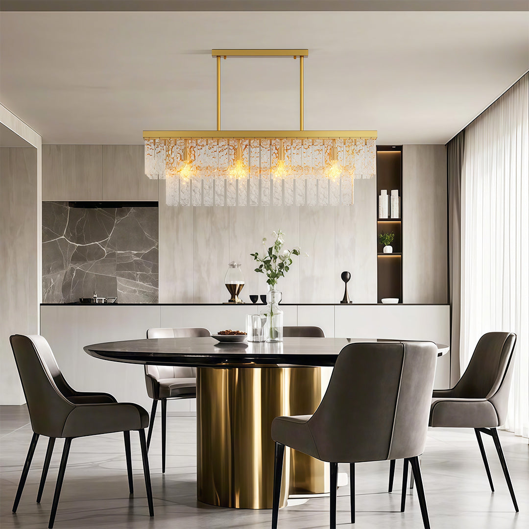 Round modern forms chandelier lighting contemporary dining space with brass table and grey chairs.