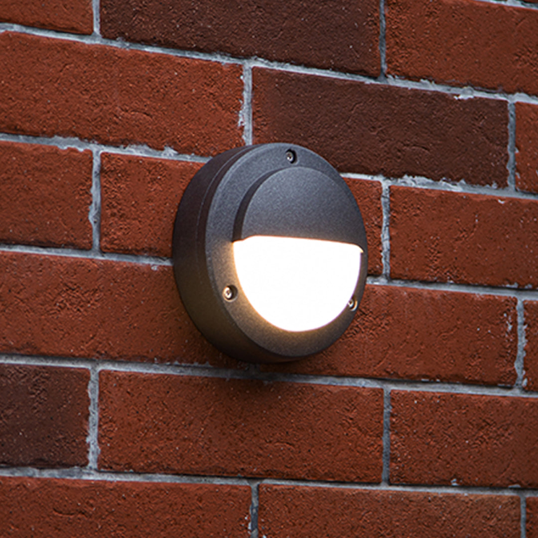 Round outdoor wall sconce creating warm accent light on red brick facade