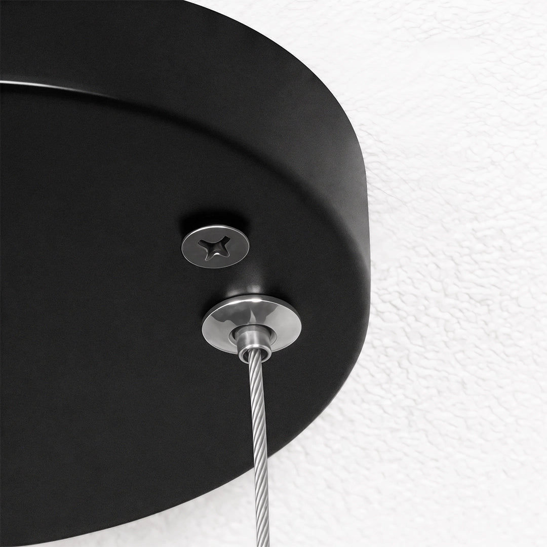 Close-up of the black ceiling canopy and hanging wire connection on round pendant lights.