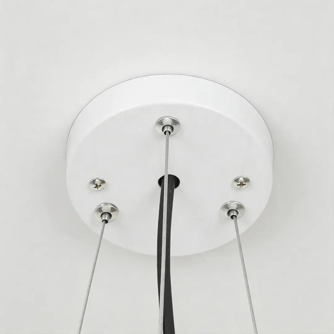 Close-up of the white ceiling canopy and suspension cables on round pendant lights.