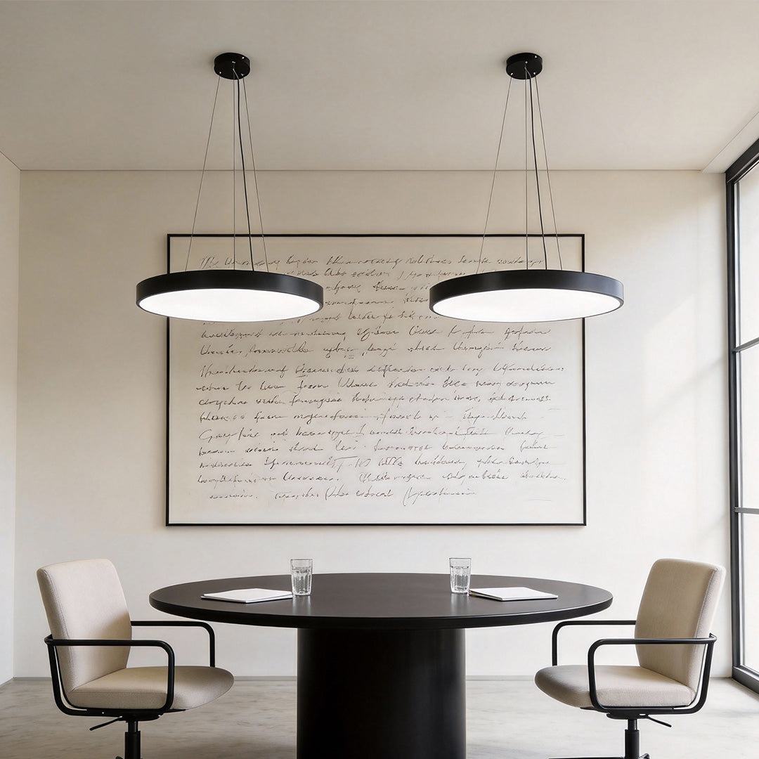 Small meeting room styled with black round pendant lights over a circular discussion table.