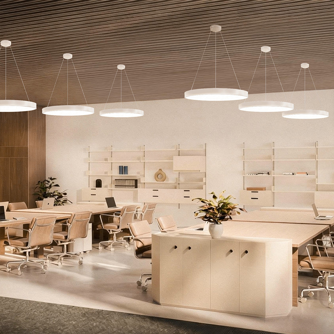 Modern office interior illuminated by round pendant lights arranged evenly above shared work tables.