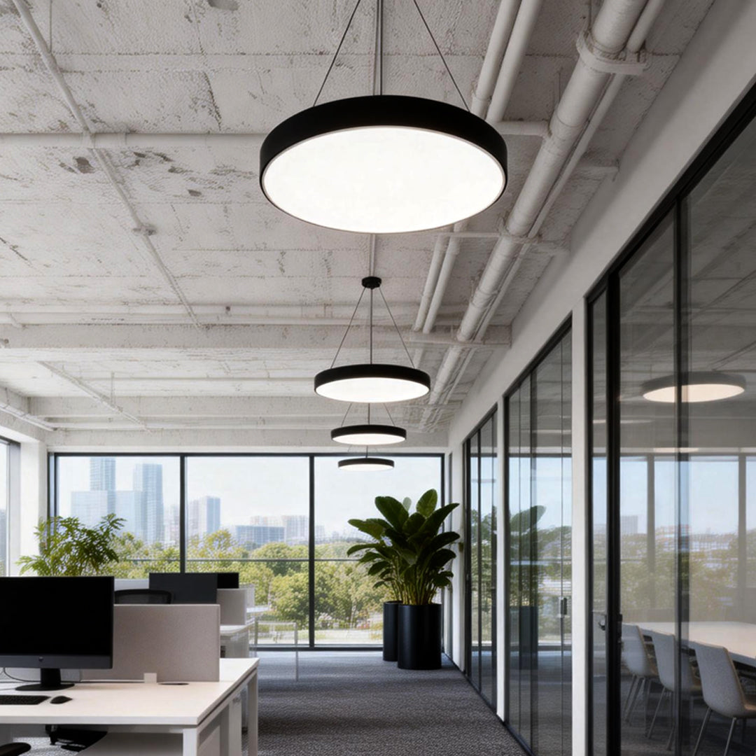 Open-plan office with concrete ceiling and round pendant lights providing soft ambient lighting.