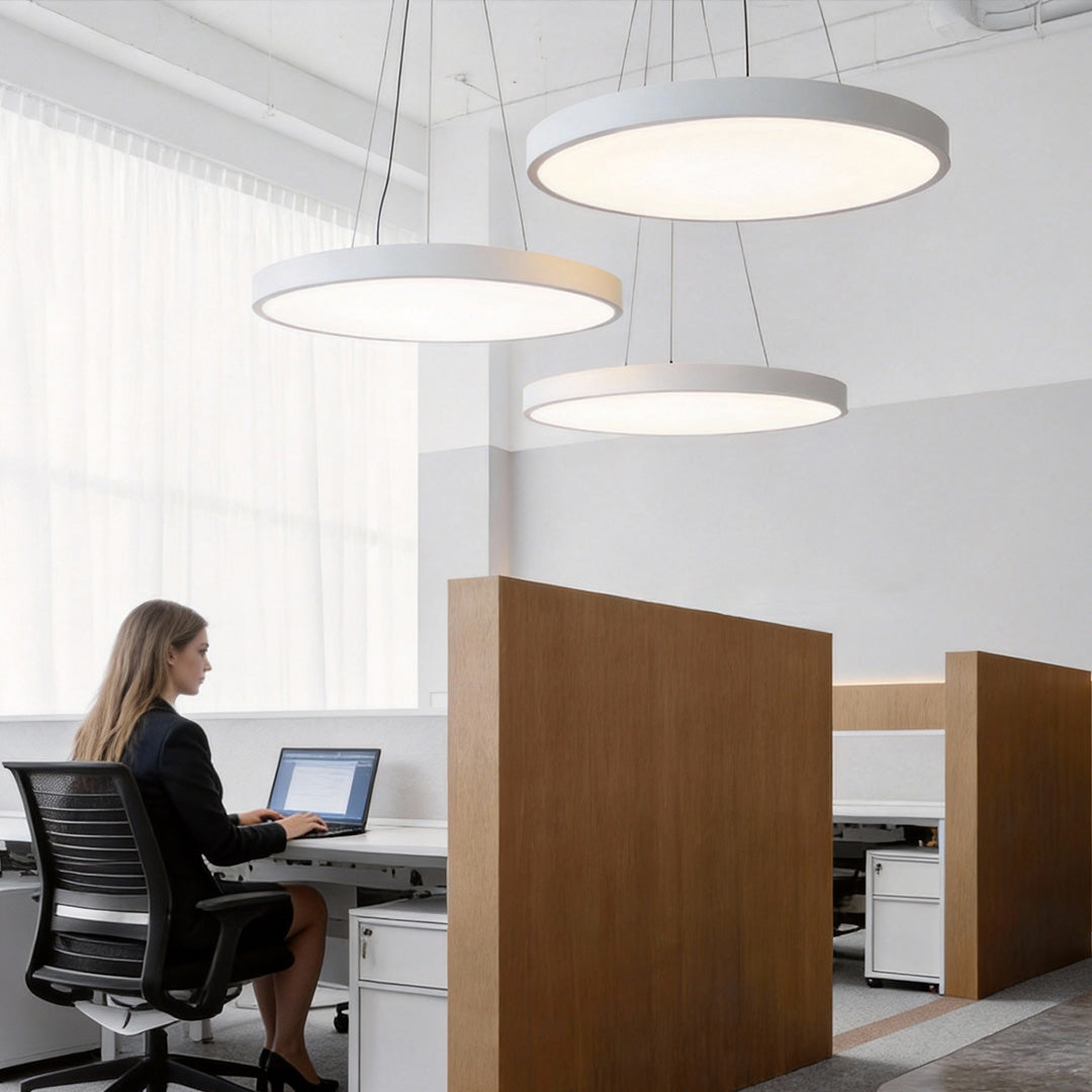 Individual workstation area illuminated by suspended round pendant lights with diffused light.