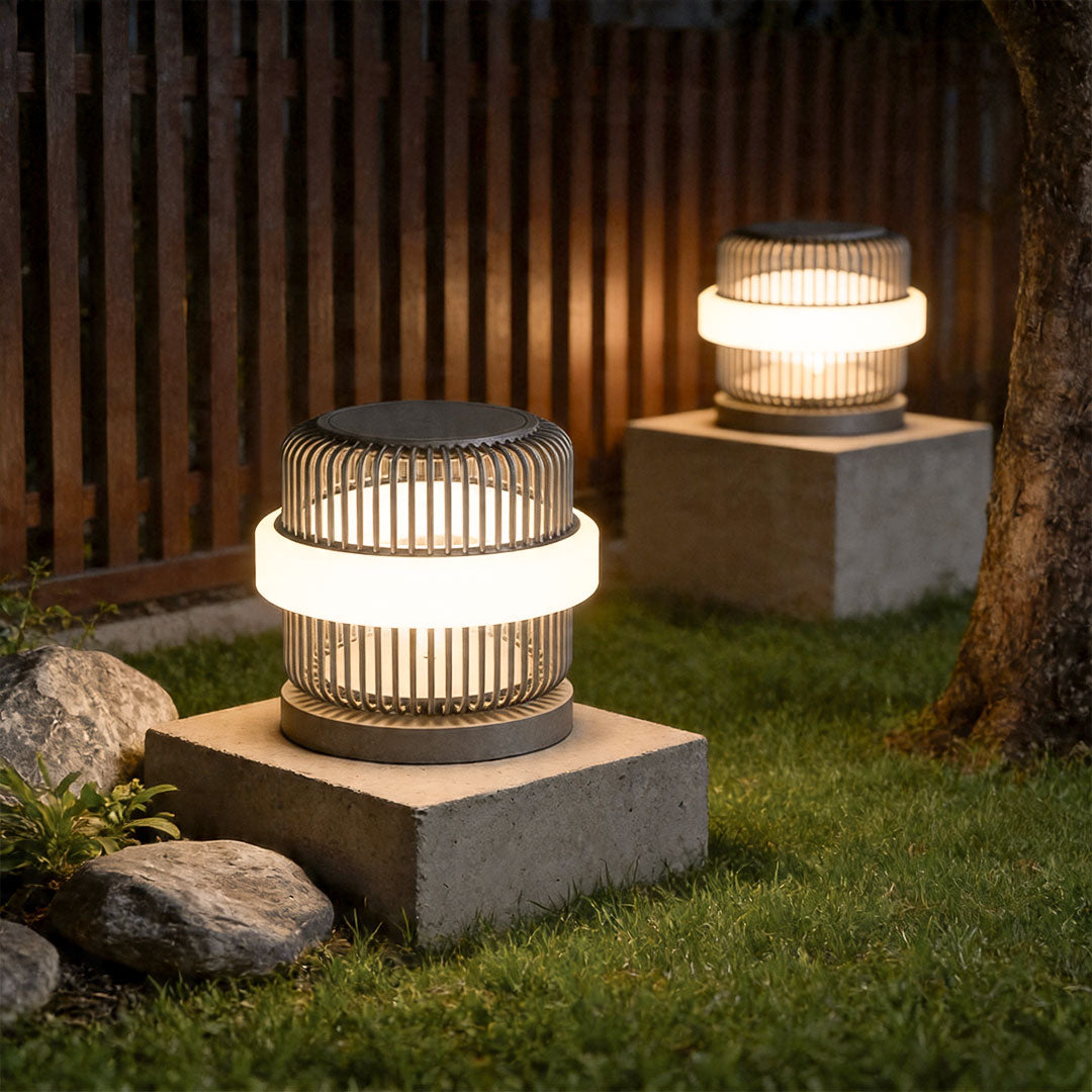 Round pillar lights outdoor beside wooden fence with warm LED glow in landscaped backyard.