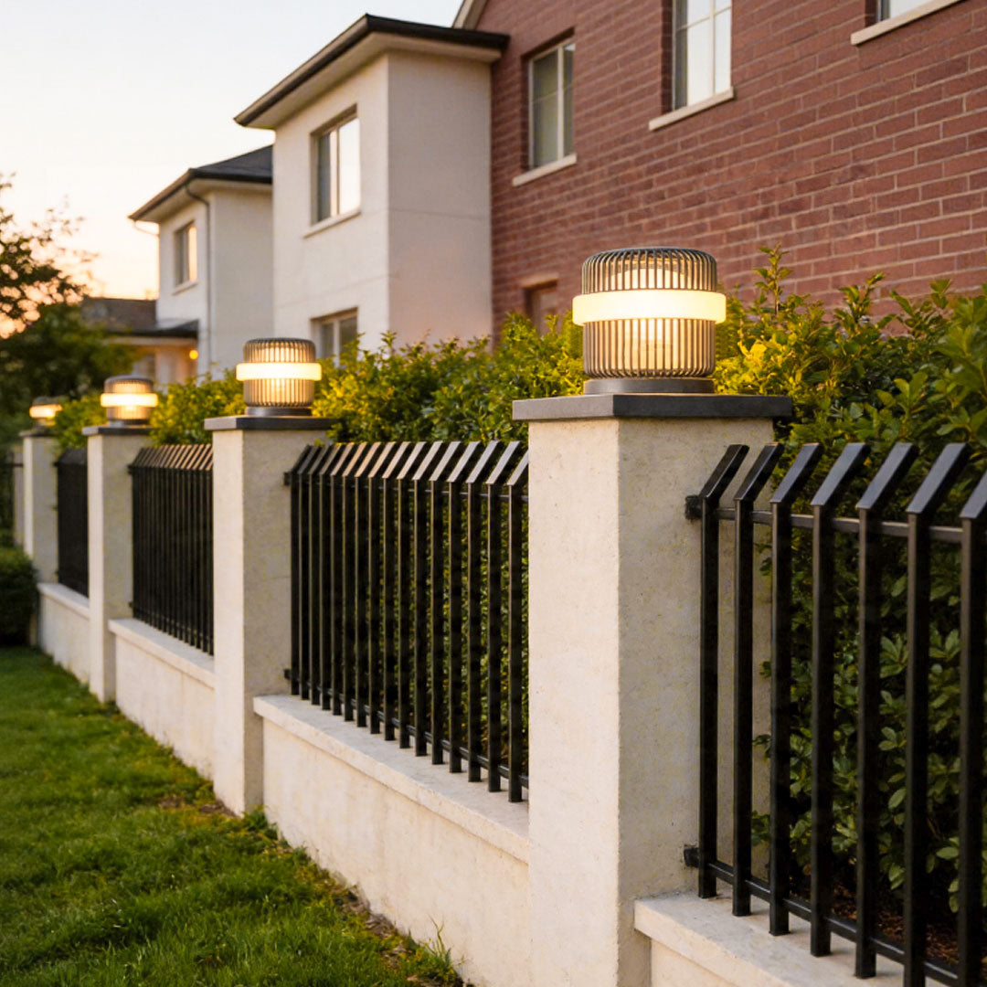 Round pillar lights outdoor installed along residential fence posts with warm ambient evening lighting.
