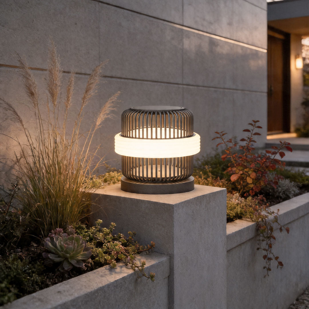 Round pillar lights outdoor illuminating a modern garden entrance with warm glow on concrete pillar.