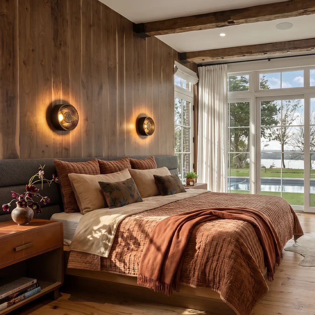 Round wall sconce pair installed on a wood paneled bedroom wall with warm decorative lighting.
