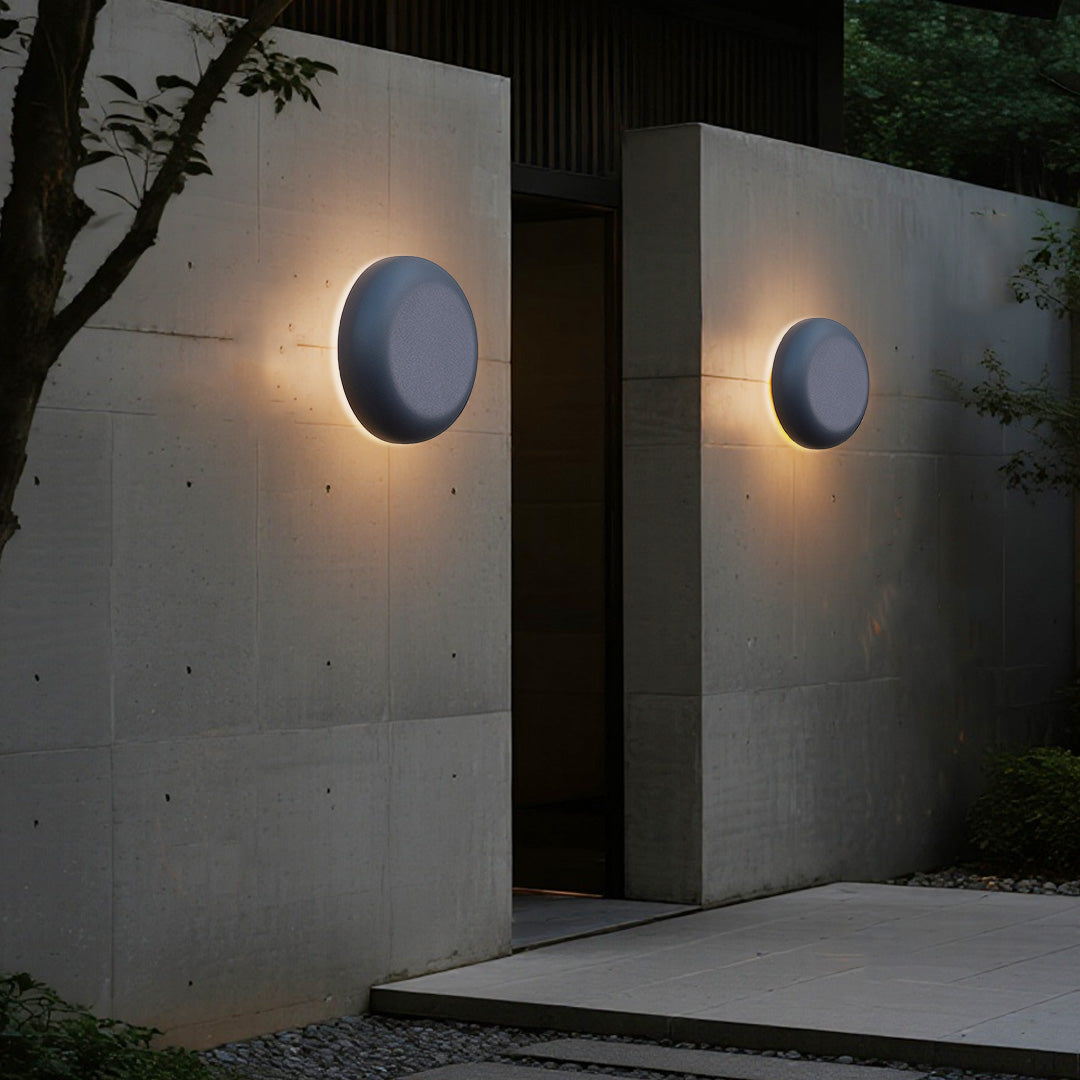 Rounded square waterproof outdoor wall light creating warm ambient glow on beige stone background
