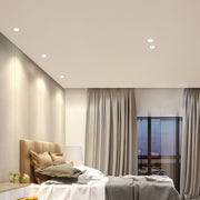 Row of adjustable downlights providing ambient lighting in beige living room with curtains and lounge chair