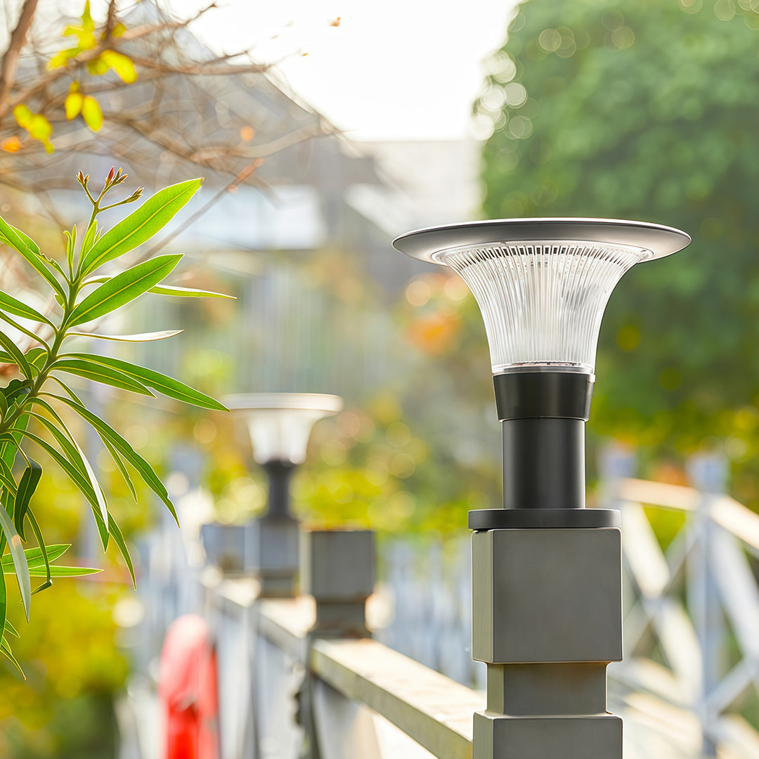 Row of black fence post cap lights with 'halo' solar panels, shown during the day on a bridge railing.