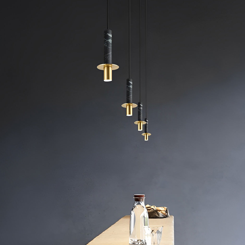 Row of four black terrazzo cylinder pendant lights with gold hardware against a dark grey wall.