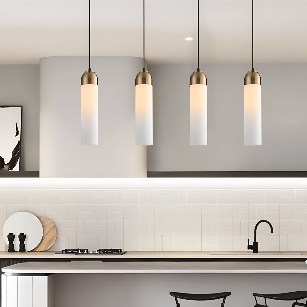 A row of four Gold Frosted Cylinder Pendant lights over a modern kitchen breakfast bar desk.