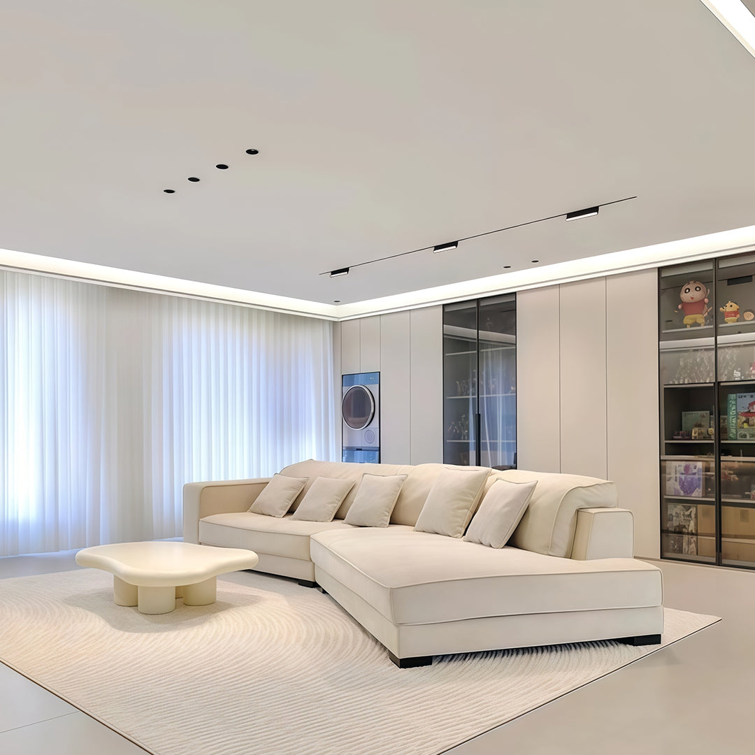 Row of LED recessed spotlights providing even illumination in spacious bedroom with sectional sofa