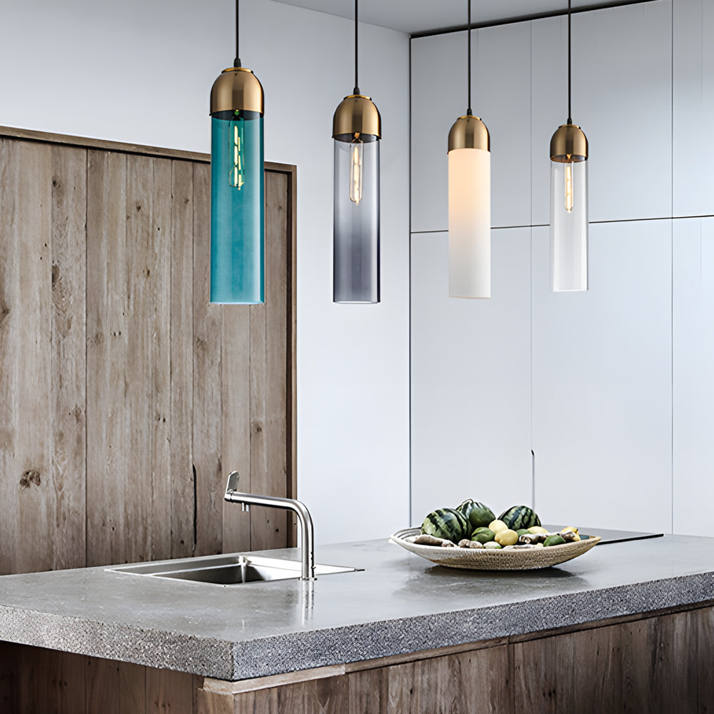 A row of four mixed Gold Frosted Cylinder Pendant lights over a modern grey kitchen island.