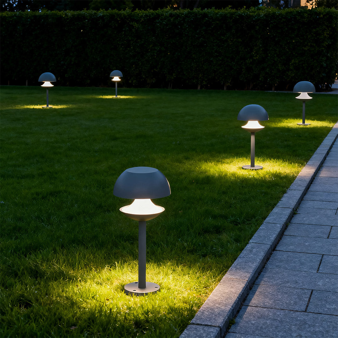 Row of mushroom path lights providing low-level illumination along garden walkway at night.