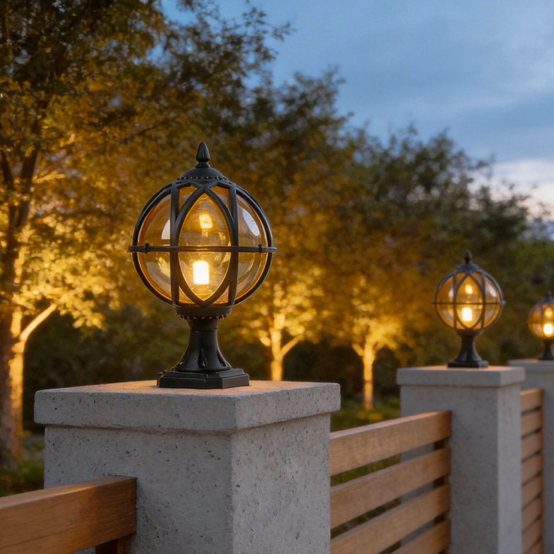 Rows of black globe pillar lights on grey pillars glowing at night along modern garden pathways.