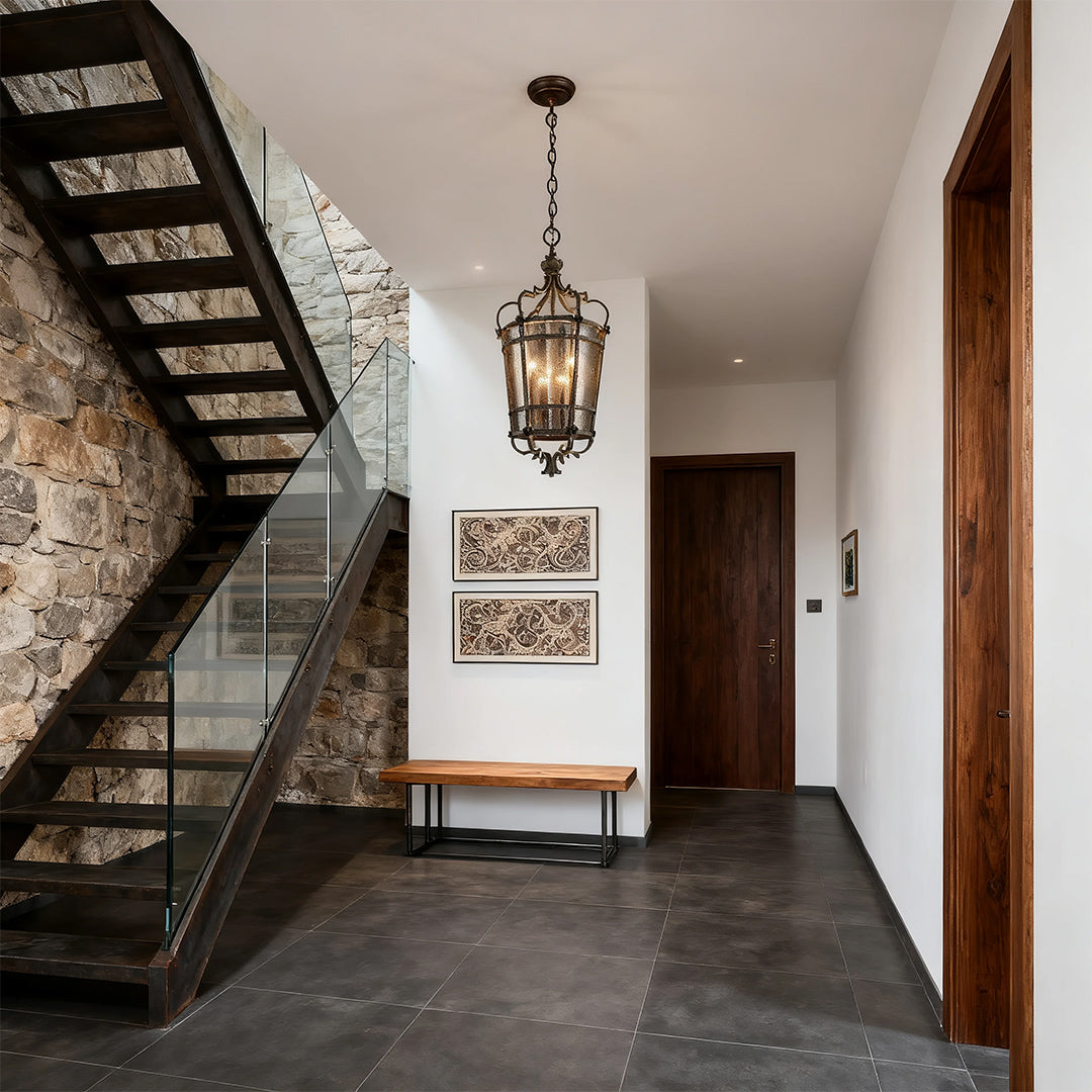 Rustic Italian pendant light with an antique bronze cage and ribbed glass panels, illuminating a modern entryway with a stone wall staircase.