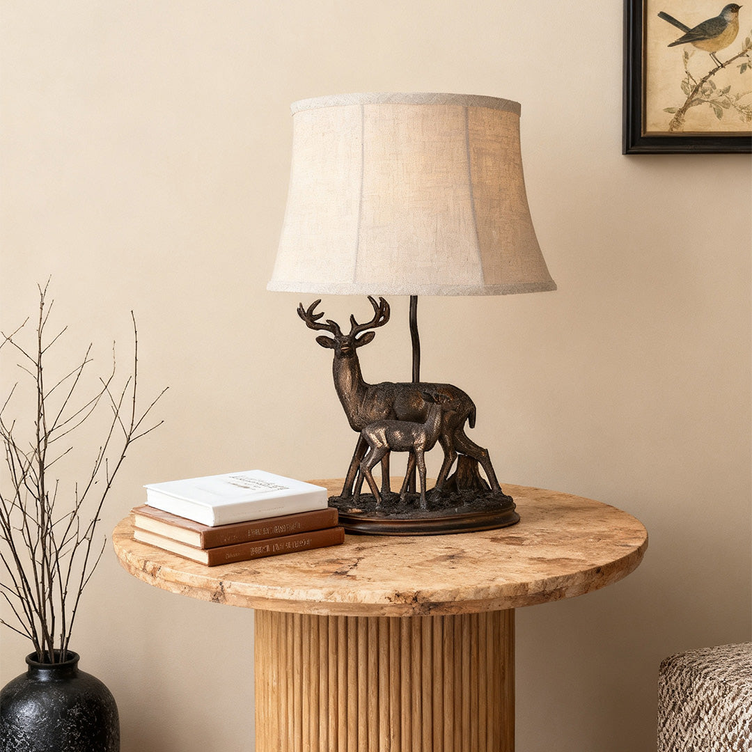 Rustic deer table lamp featuring a bronze stag and fawn figurine base and a natural linen tapered shade.