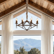 Rustic brown chandelier with a diamond-shaped iron frame and candle bulbs, suspended in a vaulted ceiling room with large scenic windows.