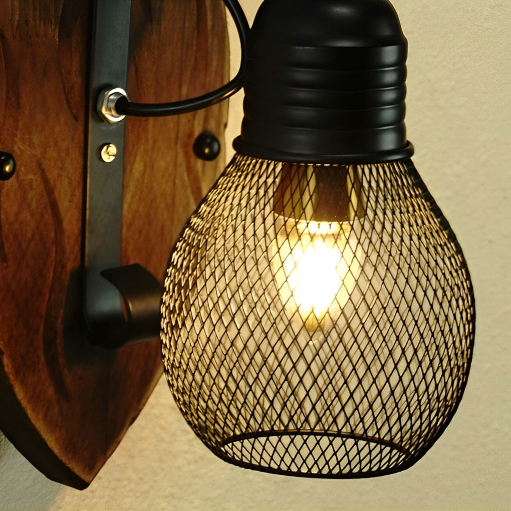 Rustic farmhouse wall sconce close-up with a black mesh teardrop shade and exposed warm bulb.