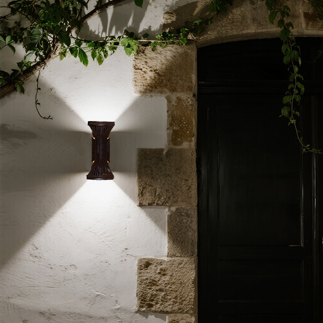 Rustic farmhouse entrance enhanced by a stylish hourglass Outdoor Wall Lighting Fixture on a textured stone wall.