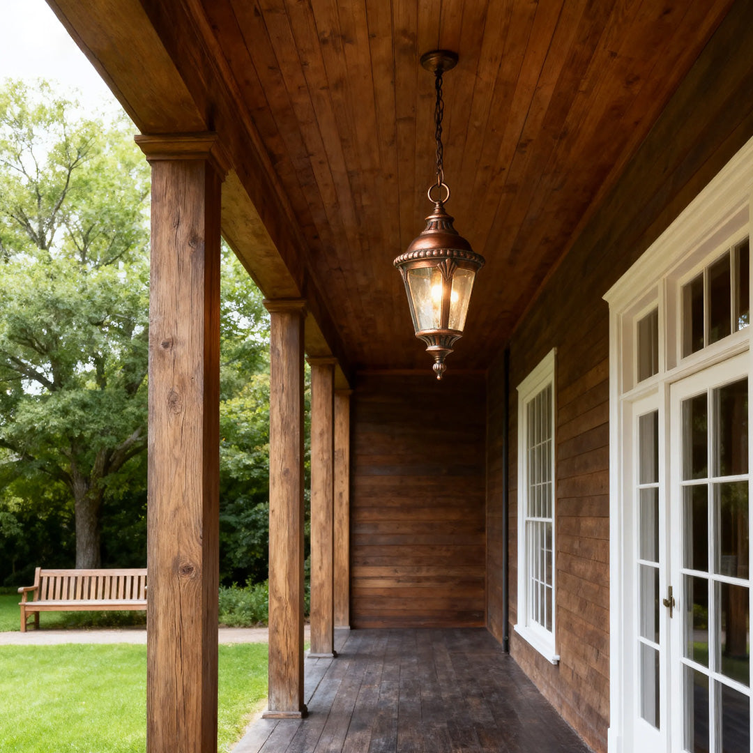Rustic industrial pendant light illuminating wood-ceiling porch with green lawn and garden view