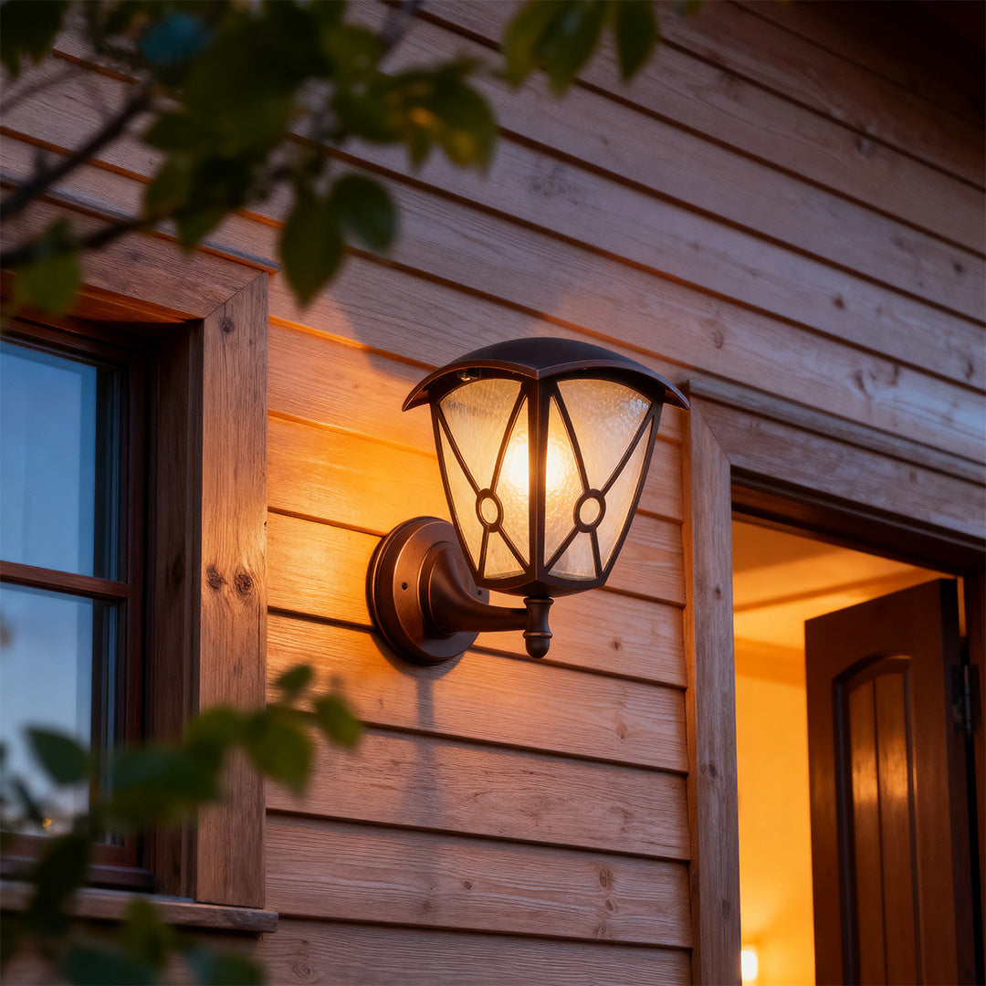 Rustic outdoor wall light for house glowing warmly on wood siding at twilight near doorway