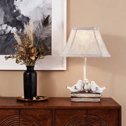 Rustic white small bird table lamp base with three birds sitting on a weathered box, placed on a wooden console table.