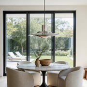 Saucer pendant light illuminating a modern dining area with warm ambient glow.