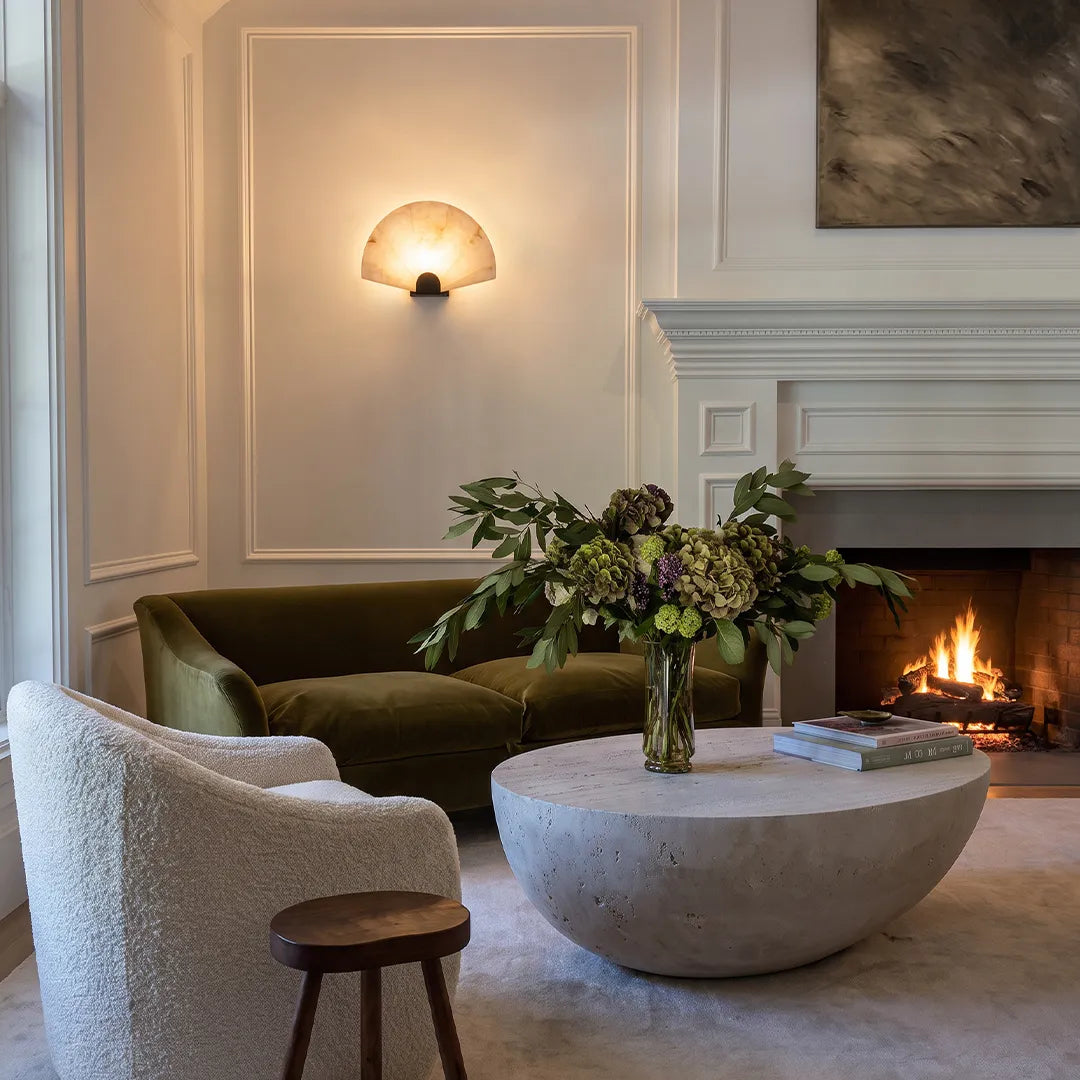 Scalloped wall sconce mounted above a fireplace in a contemporary living room with warm glow.