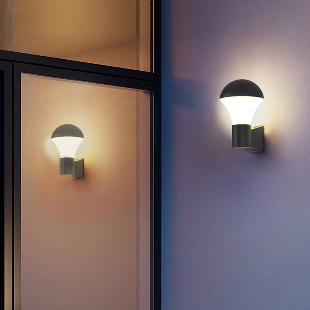 Exterior wall with warmly glowing sconce outdoor lighting fixtures providing ambient illumination at night.