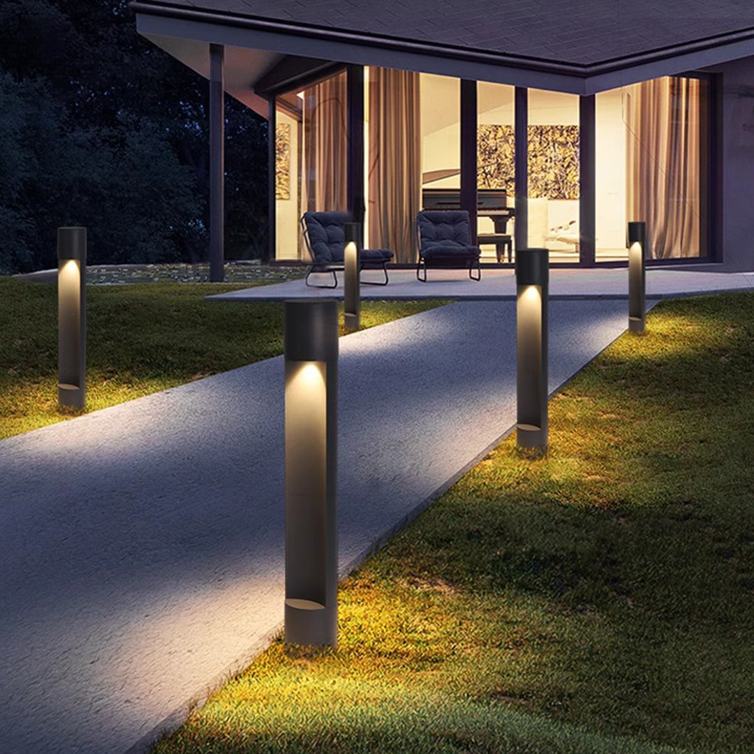Pathway illuminated by modern bollard-style sconce outdoor lighting fixtures creating warm guided lighting.