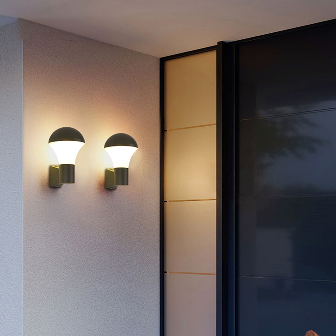Pair of modern sconce outdoor lighting fixtures mounted beside glass doors, emitting warm symmetrical light.