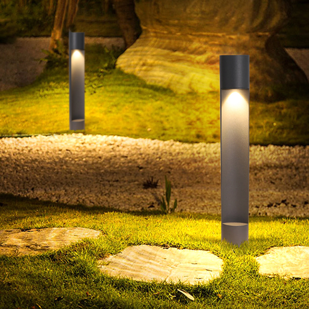 Rock garden setting with vertical sconce outdoor lighting fixtures casting warm downward illumination.
